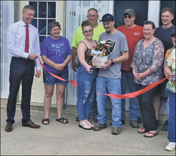 Jarrod and Brittany Schuknecht (c) of Sutherland celebrated their red ribbon cutting on May. Brittany operates a hair salon and Jarrod creates vinyl signs. Brittany cuts men's, women's and children's hair, color, perm, set and style and more. She also is set up for manicure and pedicure. Jarrod designs, cuts and adheres vinyl for store front, automobile and other signage applications. They are found at 106 Main Street or call 1712-229-3309
